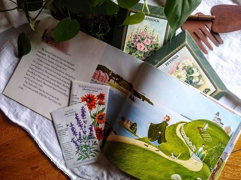 Vintage seed packets, storybook, and gardening tools on linen